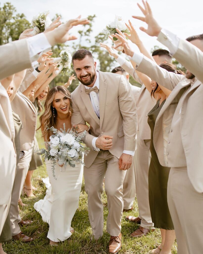 bride and groom walking through wedding party's arms